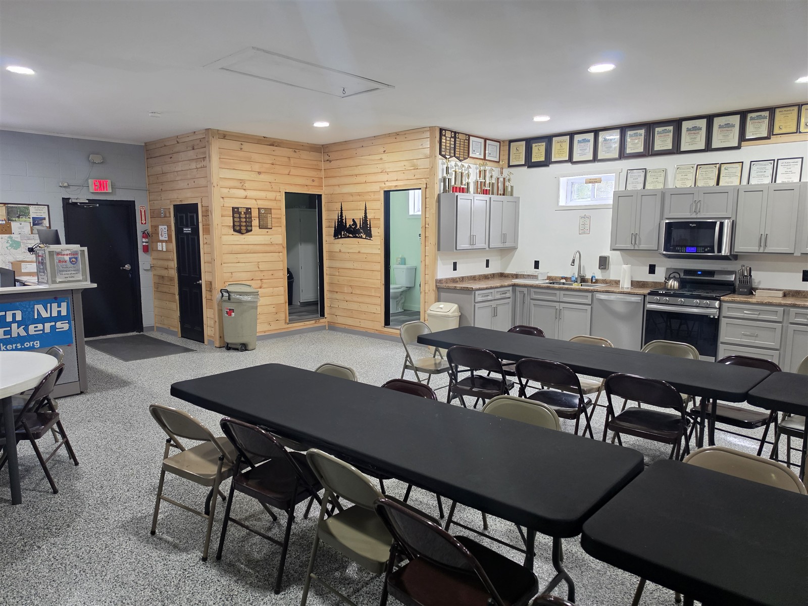 Clubhouse kitchen with light-colored cabinets, counters and adjacent wood-paneled walls.